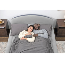 Paar schläft in einem Bett mit Lattenrost, Matratze, Kissen und Bettdecke.
