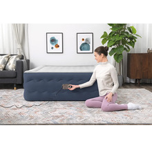 Aufblasbares Gästebett mit integrierter Pumpe in einem Wohnzimmer mit Teppich, Sofa und Dekoration.