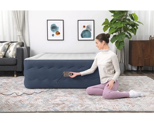 Aufblasbares Gästebett mit integrierter Pumpe in einem Wohnzimmer mit Teppich, Sofa und Dekoration.