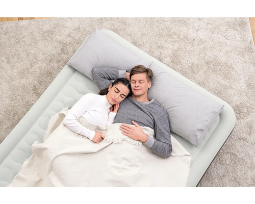 Ein Paar schläft auf einer Luftmatratze mit Kissen und Decke.