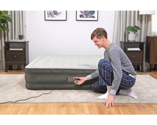 Mann bedient eine aufblasbare Matratze mit integrierter Pumpe im Schlafzimmer.