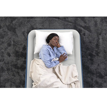 Luftmatratze mit schlafender Person, Kissen und Decke auf einem Teppich