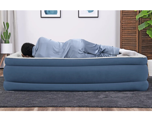 Person liegt auf einer blauen Luftmatratze im Raum.