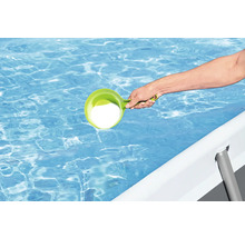Person fügt Poolchemie mit einem Dosierbecher in einen Pool hinzu