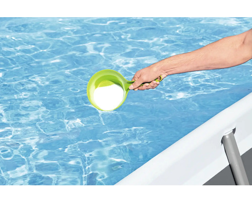 Person fügt Poolchemie mit einem Dosierbecher in einen Pool hinzu
