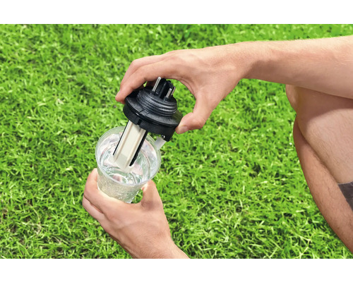 Eine Person testet einen Wasserstandsmelder in einem mit Wasser gefüllten Becher.