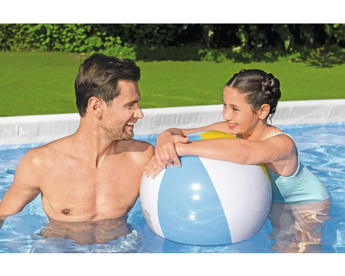Vater und Tochter spielen mit einem Ball im Pool.