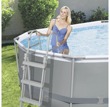 Frau steigt mit einer Leiter in einen Stahlrahmenpool im Garten.