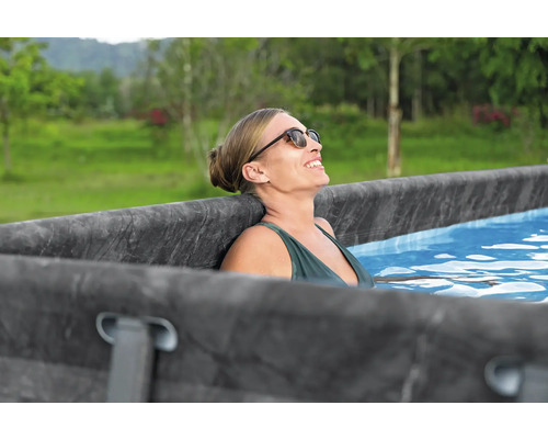 Frau entspannt in einem Frame-Pool im Garten.