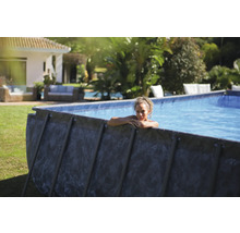 Aufstellpool im Garten mit einer Frau, die sich am Beckenrand ausruht.