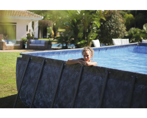 Aufstellpool im Garten mit einer Frau, die sich am Beckenrand ausruht.
