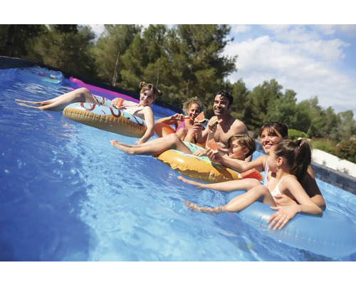 Familie entspannt sich mit Wassermelone auf Schwimmringen im Pool.