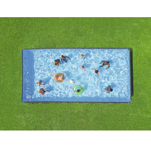Draufsicht auf einen rechteckigen Pool mit mehreren Personen, Schwimmringen und einem Ball auf einer grünen Rasenfläche.
