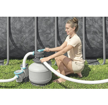 Frau bedient eine Sandfilteranlage für einen Pool im Garten.