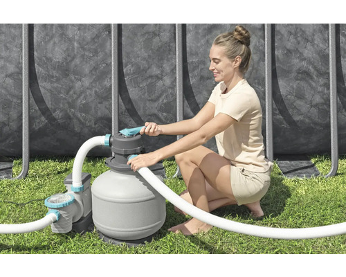 Frau bedient eine Sandfilteranlage für einen Pool im Garten.