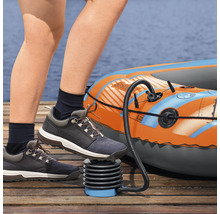 Person pumpt ein Schlauchboot mit einer Fußpumpe auf einem Holzsteg auf.