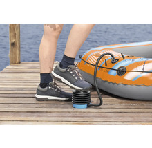 Person pumpt ein aufblasbares Boot mit einer Fußpumpe auf einem Holzsteg auf.