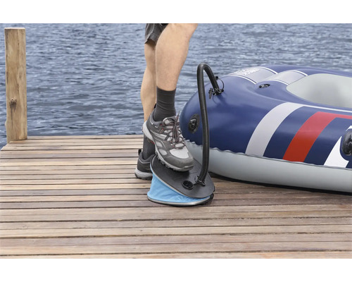 Person bedient Fußpumpe neben aufgeblasenem Schlauchboot