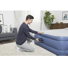 Mann pumpt Luftmatratze im Wohnzimmer auf.