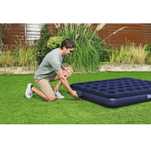 Ein Mann pumpt eine blaue Luftmatratze im Garten auf