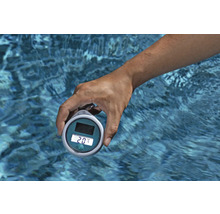 Eine Hand hält ein digitales Poolthermometer über Wasser.