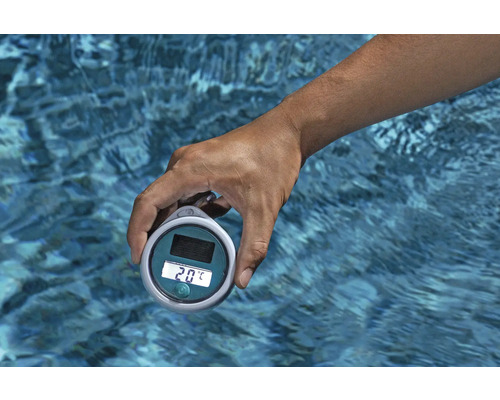 Eine Hand hält ein digitales Poolthermometer über Wasser.