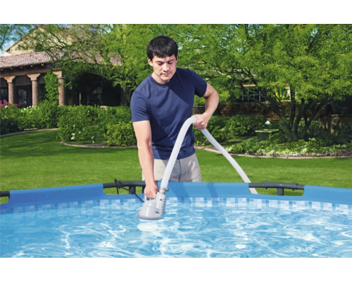 Mann reinigt Pool mit Poolsauger im Garten.