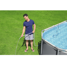 Mann befüllt Pool mit einem Wasserschlauch auf einer Rasenfläche.