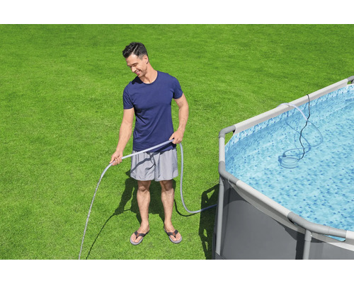 Mann befüllt Pool mit einem Wasserschlauch auf einer Rasenfläche.
