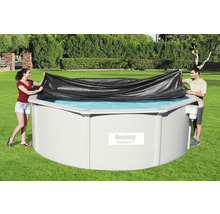 Personen decken ein rundes Schwimmbecken mit einer Poolabdeckung ab.