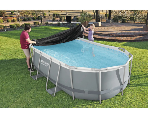 Personen legen eine Schutzplane auf einen rechteckigen Pool im Garten