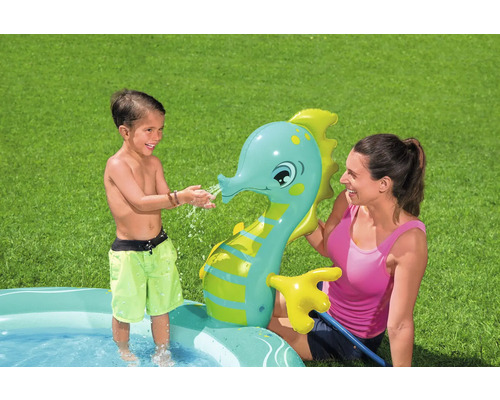 Kind spielt mit aufblasbarem Seepferdchen-Wassersprinkler in einem Planschbecken
