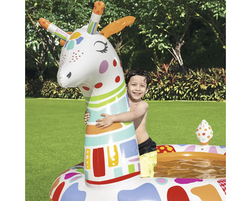 Kind umarmt aufblasbare Giraffe in buntem Planschbecken im Garten