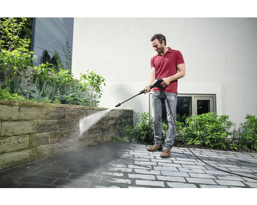 Mann reinigt Terrasse mit Hochdruckreiniger.