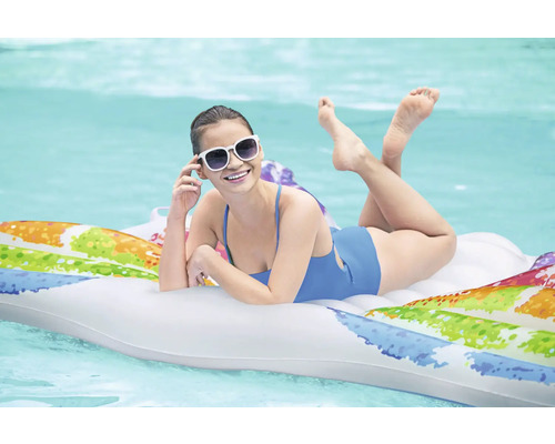 Frau mit Sonnenbrille liegt auf einer aufblasbaren Matratze im Wasser.