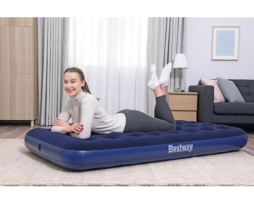Frau liegt auf einer blauen Bestway Luftmatratze im Wohnzimmer.
