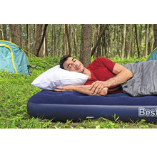 Mann schläft auf einer Luftmatratze mit Schlafsack und Kissen beim Camping