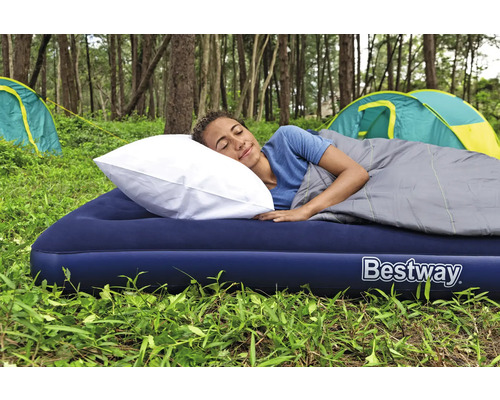 Frau schläft auf einer Luftmatratze mit Kissen und Schlafsack im Freien, mit dem Bestway Logo.