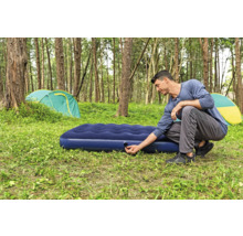 Mann bereitet Luftmatratze zum Campen in der Natur vor.