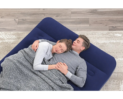 Ein Paar liegt auf einer blauen Luftmatratze unter einer grauen Decke.