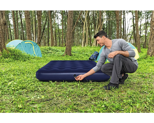 Mann bereitet Luftmatratze im Wald zum Campen vor