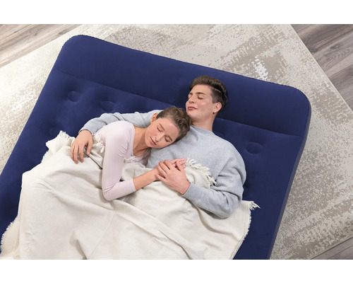 Ein Paar schläft auf einer blauen Luftmatratze auf einem Teppich.