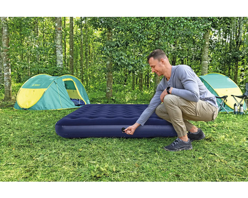 Mann bereitet Luftmatratze zum Campen vor einem Zelt vor