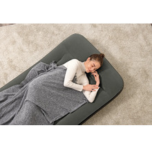 Frau schläft auf Luftmatratze mit Decke auf einem Teppich