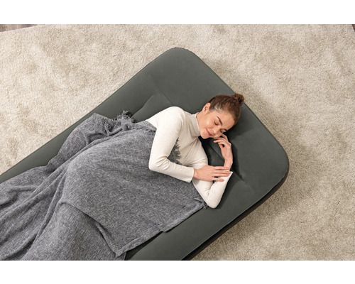 Frau schläft auf Luftmatratze mit Decke auf einem Teppich