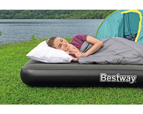 Frau schläft auf einer Luftmatratze im Freien mit Schlafsack, Kissen und Zelt im Hintergrund. Marke Bestway.