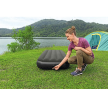Frau pumpt eine Luftmatratze auf einem Campingplatz auf