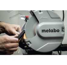 Mann schleift Metallstück an Doppelschleifer der Marke Metabo