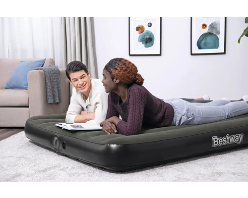 Zwei Personen entspannen sich auf einer Luftmatratze im Wohnzimmer.