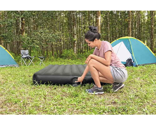 Frau bereitet eine Luftmatratze zum Campen vor einem Zelt vor